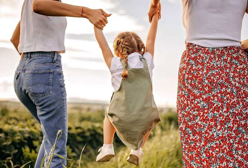The women lift the child up by the hands.